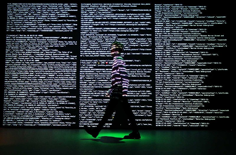 LONDON, ENGLAND - DECEMBER 02:  A staff member stands in a projection of live data feeds from (L-R) Twitter, Instagram and Transport for London by data visualisation studio Tekja at the Big Bang Data exhibition at Somerset House on December 2, 2015 in London, England. The show highlights the data explosion that's radically transforming our lives. It opens on December 3, 2015 and runs until February 28, 2016 at Somerset House.  (Photo by Peter Macdiarmid/Getty Images for Somerset House)